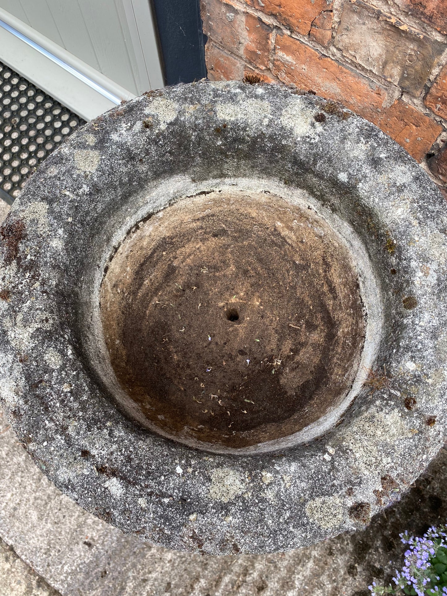 Weathered stone urn photographed from above to show drainage hole 