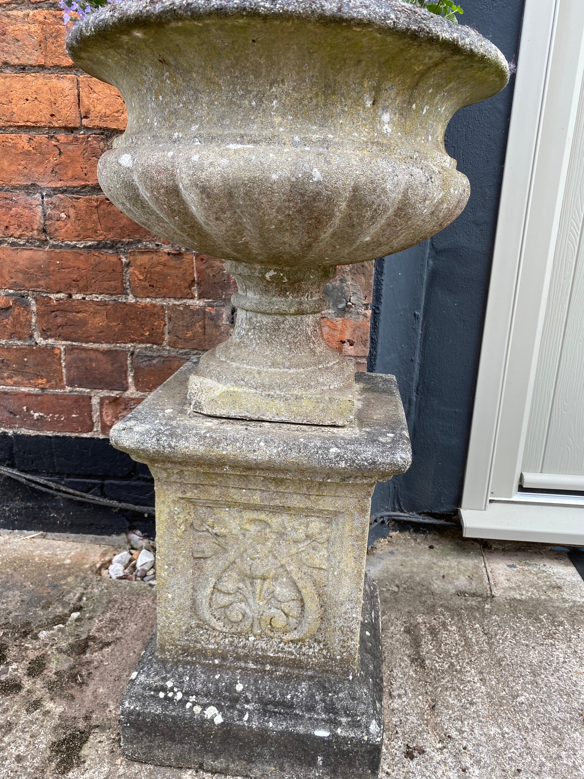 Decorative stone urn with house behind