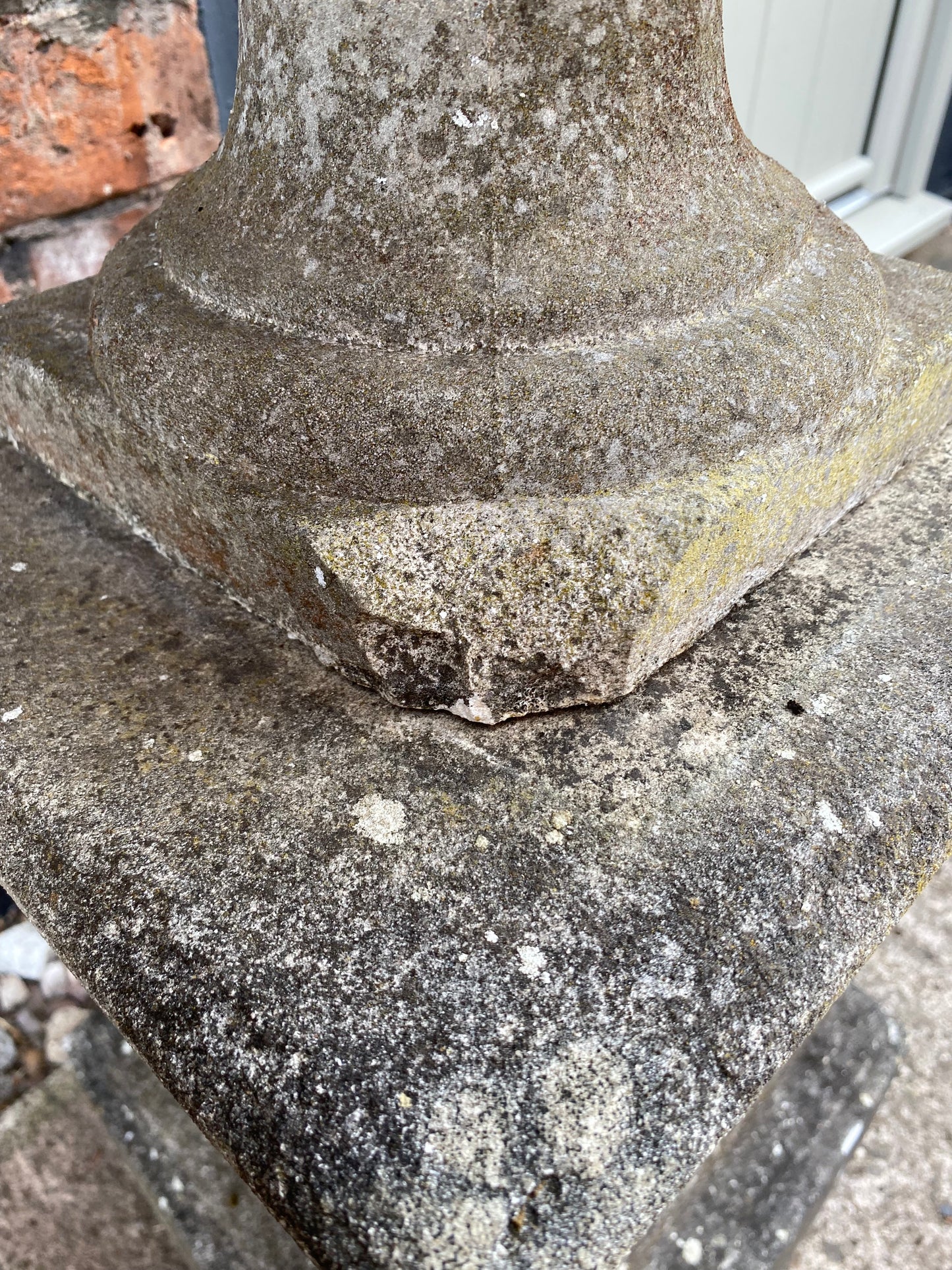 Close-up of a textured stone urn with visible old damage and lichen.